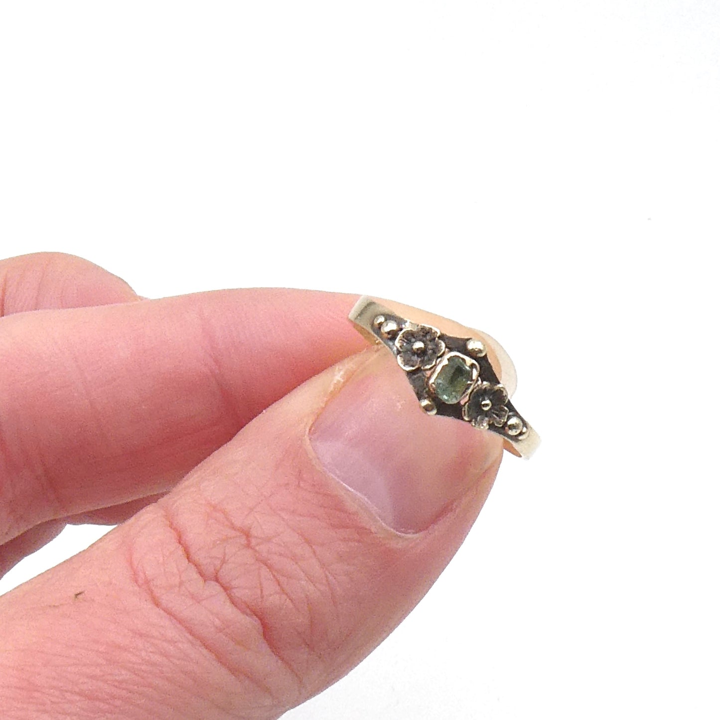Antique ring with etched flowers and a small rectangular emerald.