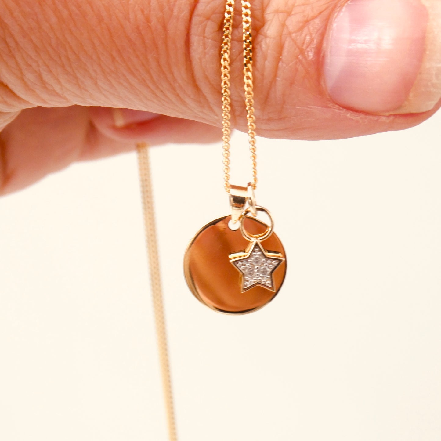 A Gold Disc Pendant with a 9kt gold and diamond star charm, diamond is the April Birthstone.