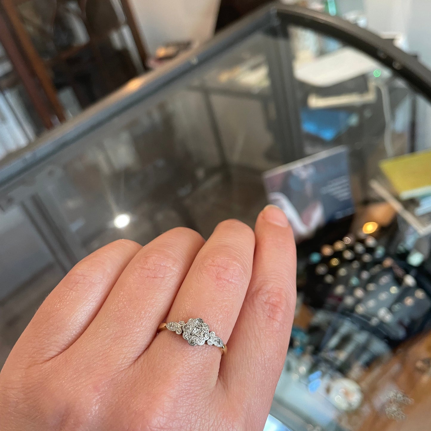 A flower ring with a patterned platinum face set with tiny flat diamonds.