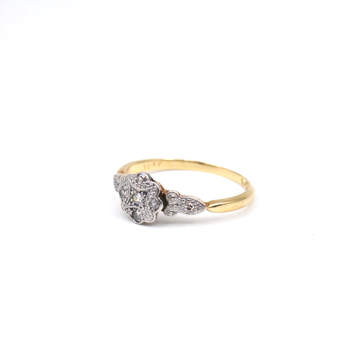 A flower ring with a patterned platinum face set with tiny flat diamonds.