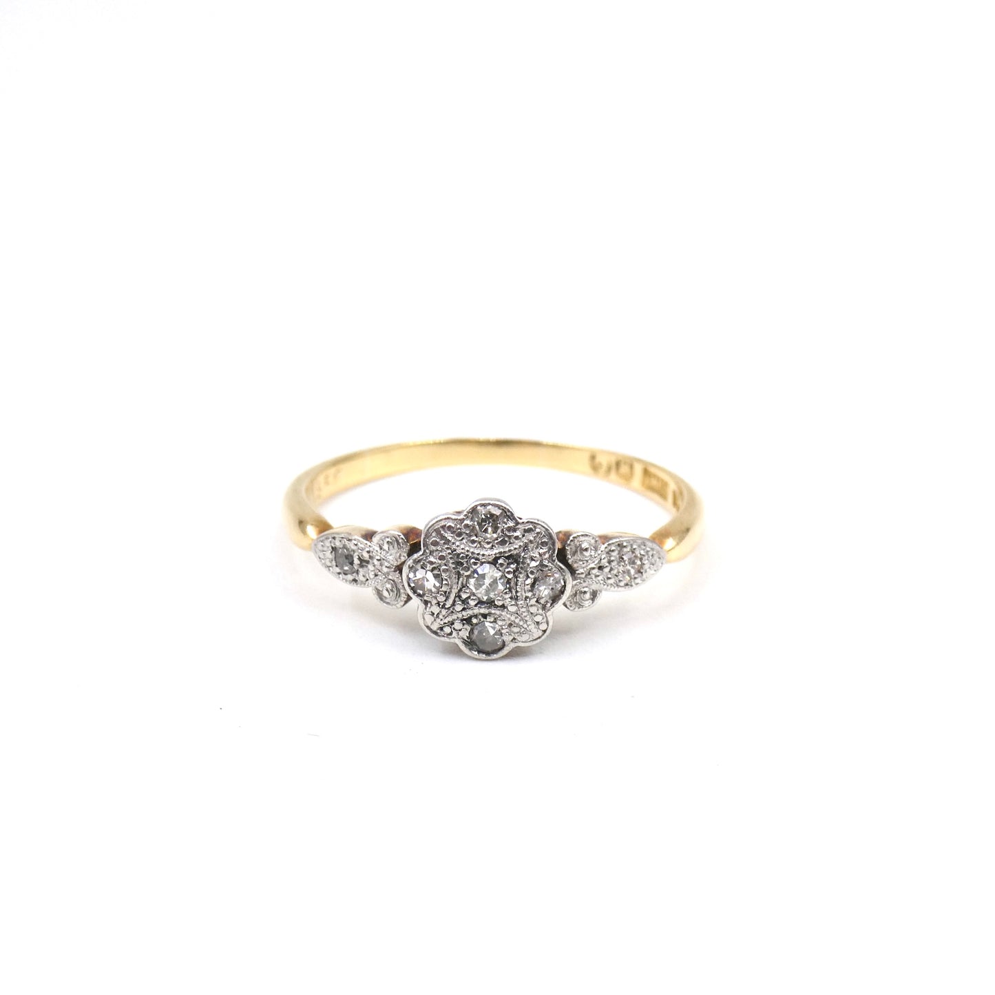 A flower ring with a patterned platinum face set with tiny flat diamonds.