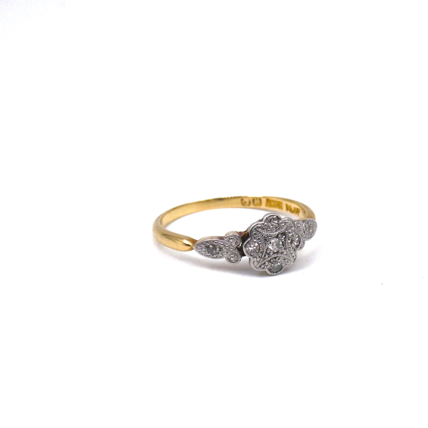 A flower ring with a patterned platinum face set with tiny flat diamonds.