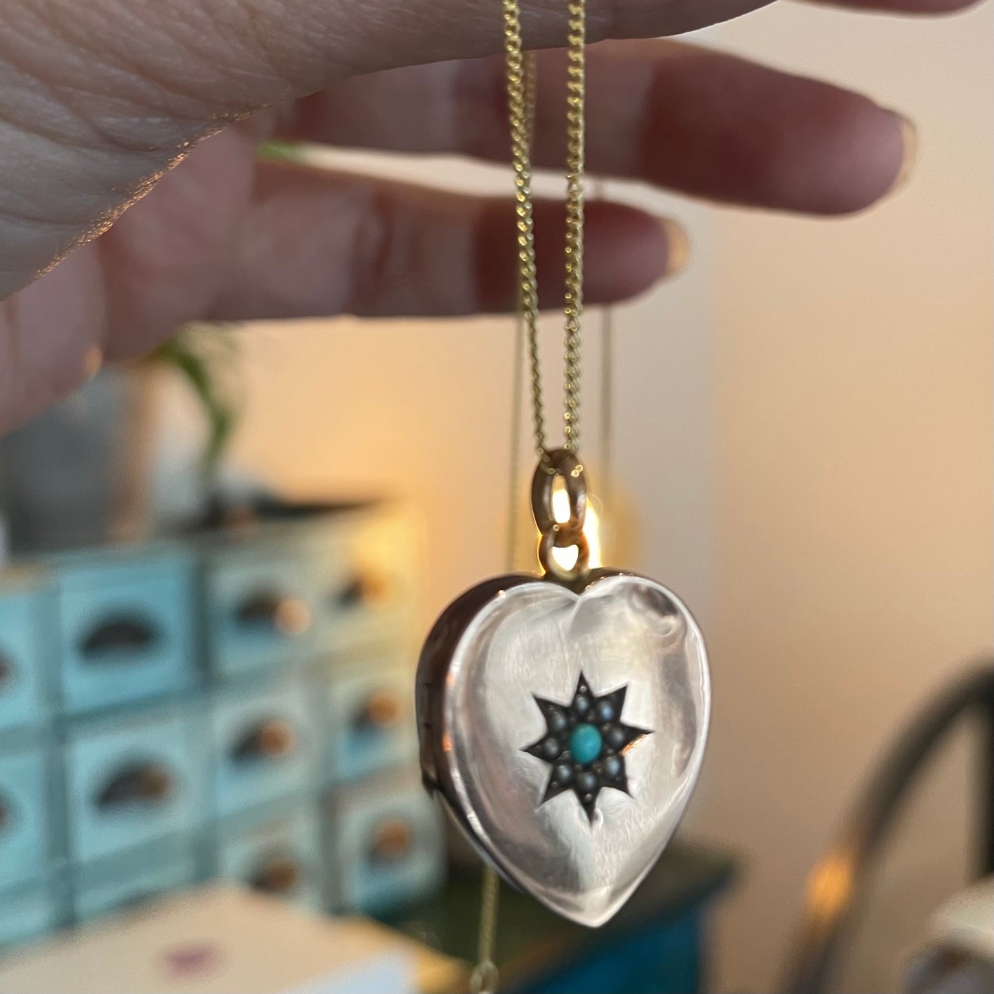 Antique Heart Locket and a turquoise and split pearl star set motif, on a 9kt gold chain.