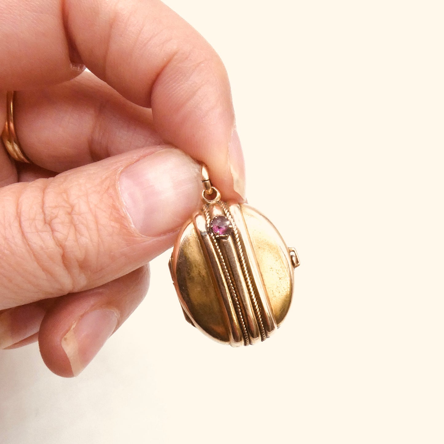 Antique oval locket with a double raised rope stripe and a garnet set gem, locket from the 1800's