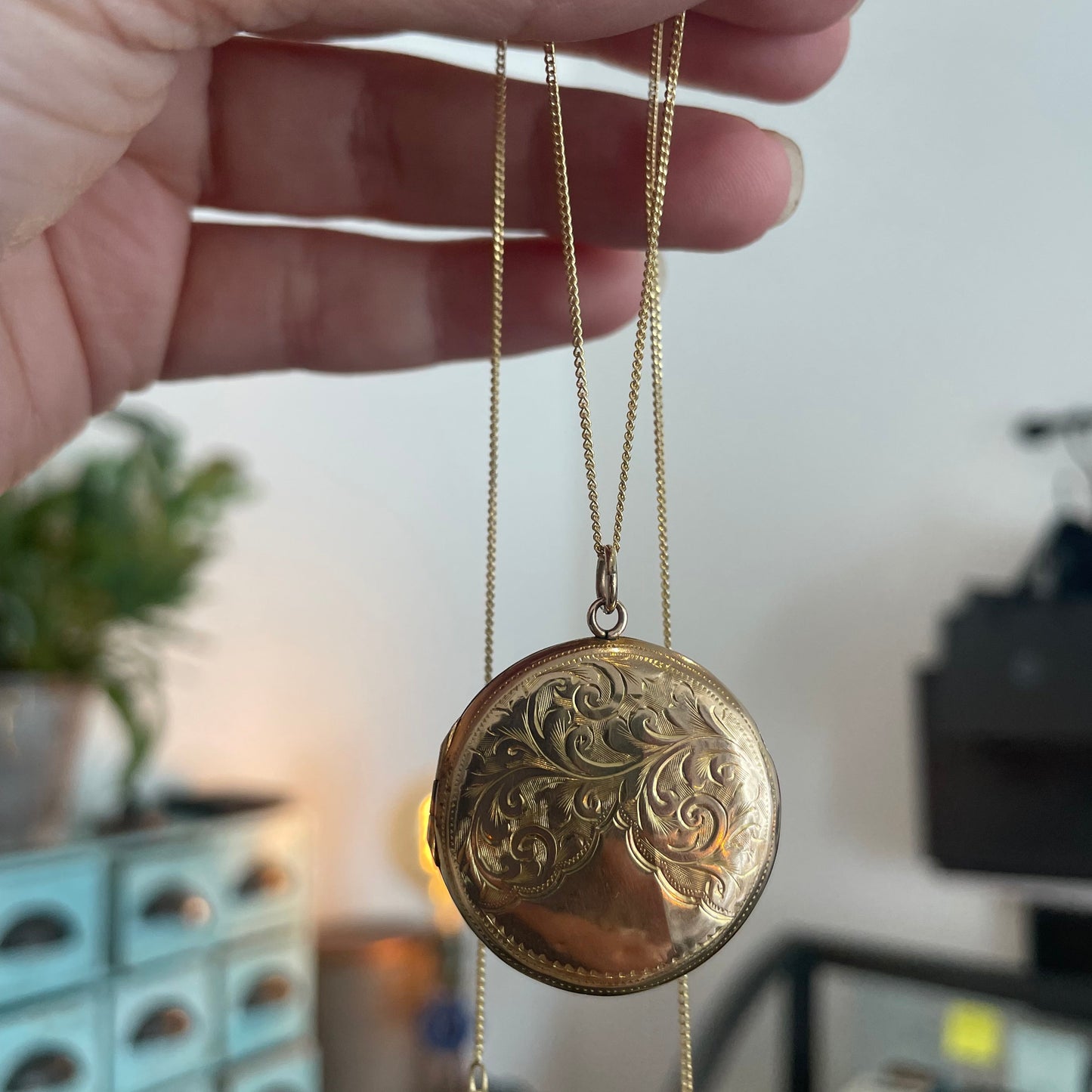 Victorian round locket with an elegant scroll motif, on a 9kt gold chain.