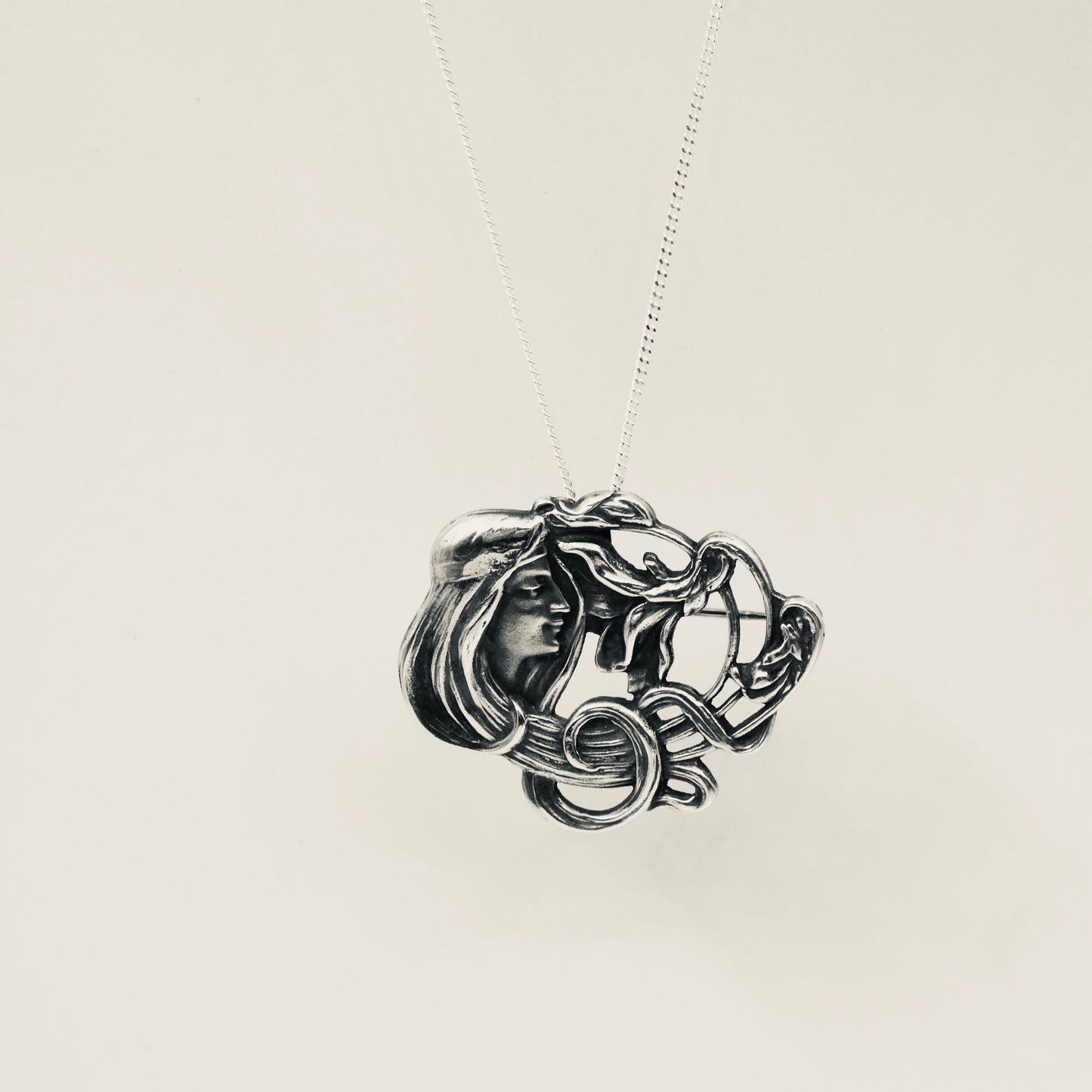 An Art Nouveau style pendant/brooch in sterling silver.