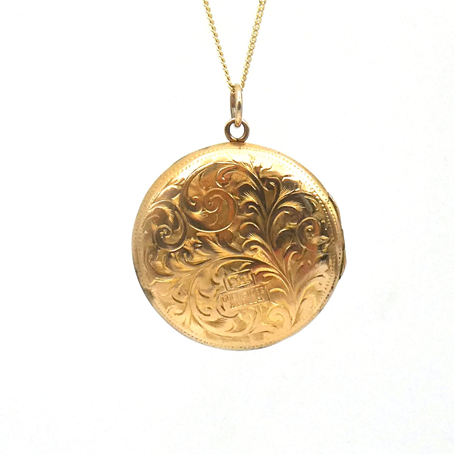 Victorian round locket with an elegant scroll motif, on a 9kt gold chain.