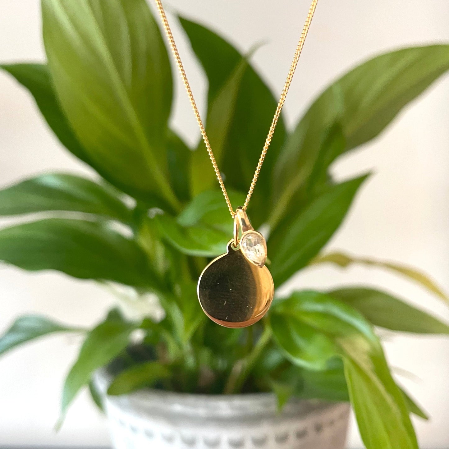 Gold disc necklace with a white topaz charm, for an April Birthday