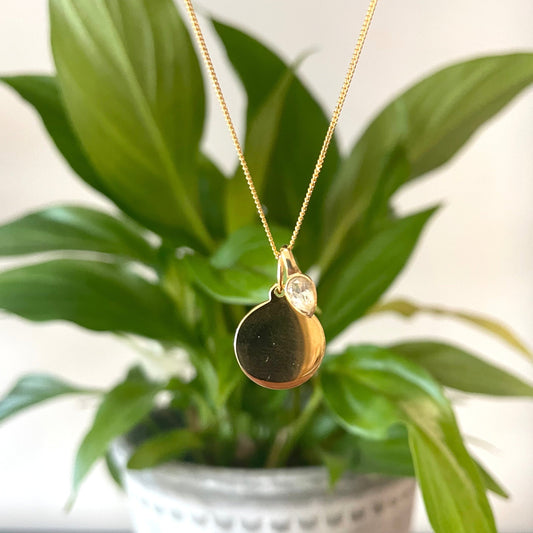 Gold disc necklace with a white topaz charm, for an April Birthday