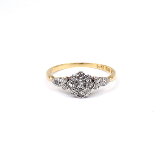 A flower ring with a patterned platinum face set with tiny flat diamonds.